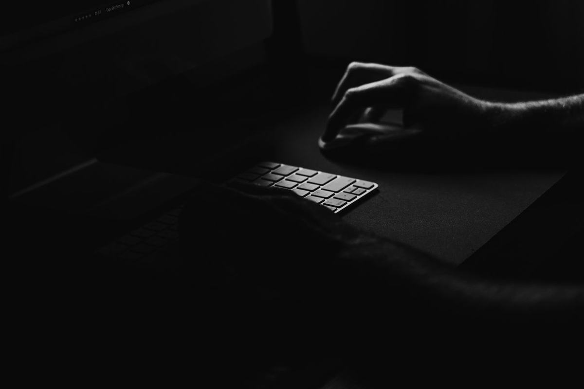 Tangan mengetik pada papan tuts laptop dalam gelap, melambangkan keamanan data