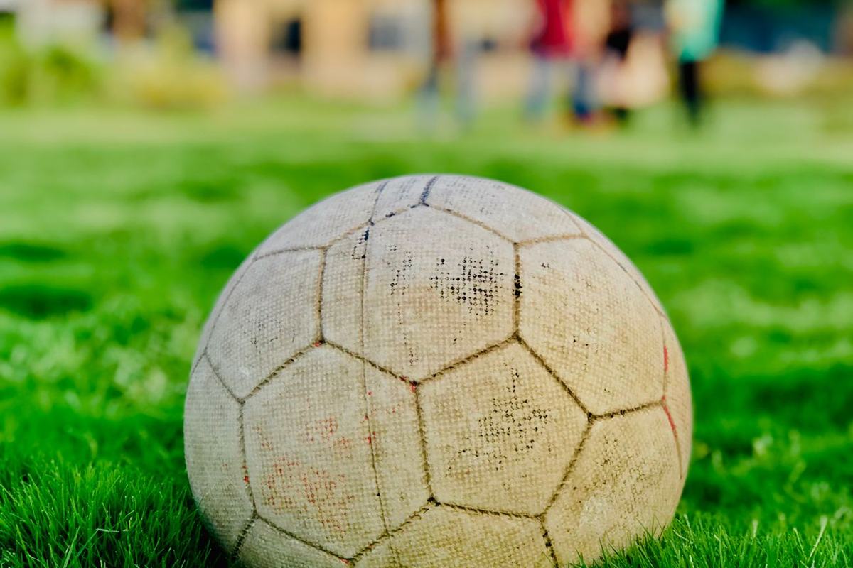 Bola sepak di atas rerumputan hijau dengan stadion di latar belakang